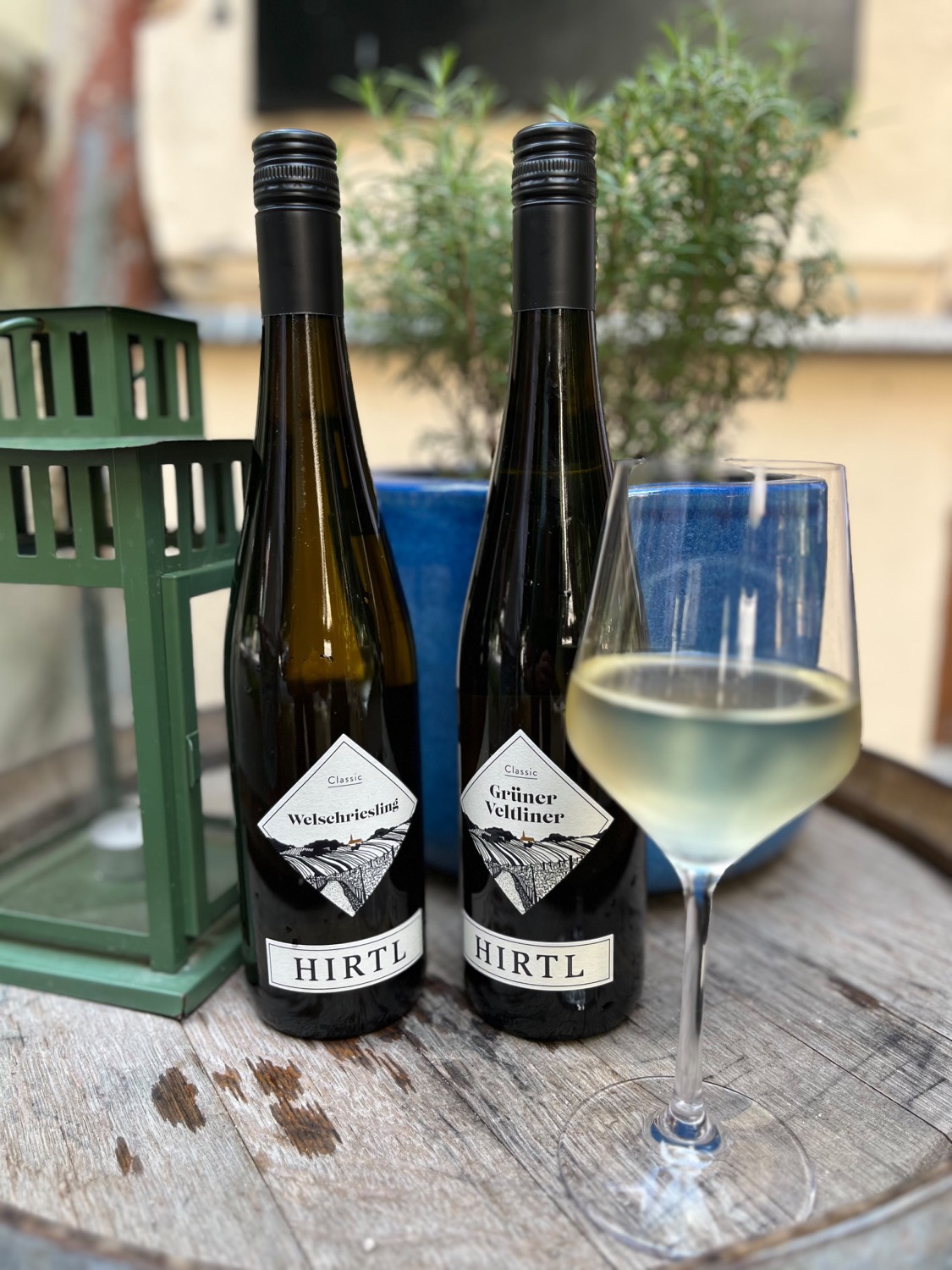 Láhve Grüner Veltliner a Welschriesling od Weingut Hirtl se sklenkou bílého vína v LŌKAHI